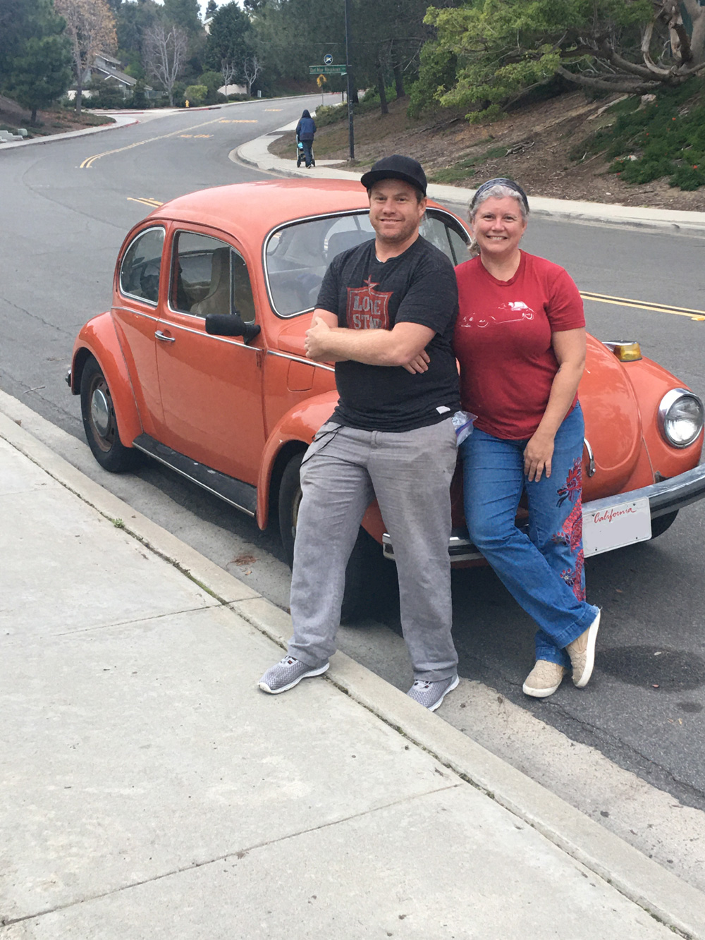 Erika and her husband with orange Super Beetle