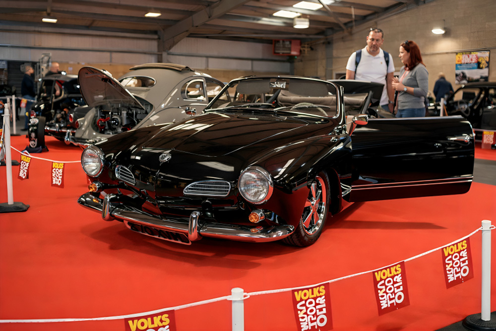 Classic VW buses and Beetles displayed indoors at the Volksworld Show.