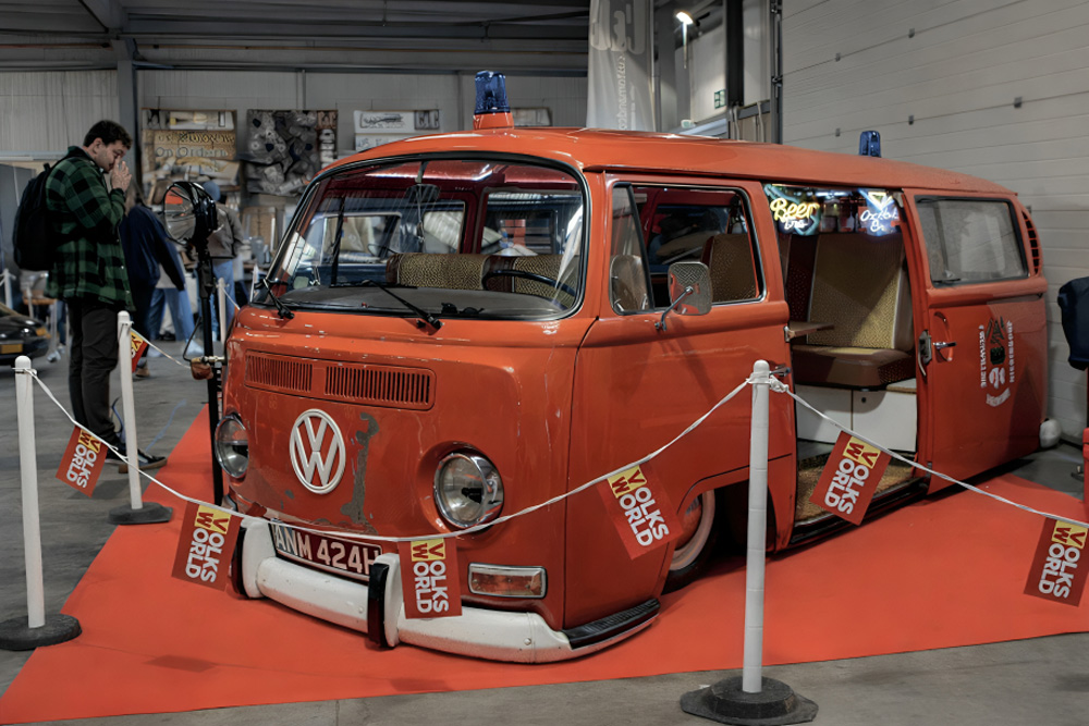 Visitors outside the Volksworld Show entrance with classic cars on display.